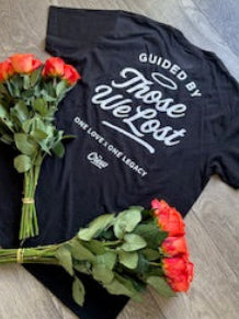 Black t-shirt with white text on a wooden floor with red roses.